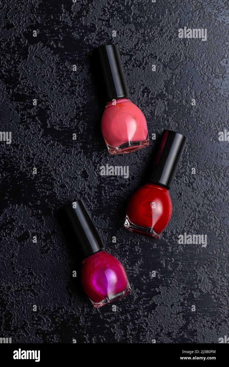 Colorful nail polish bottles on a black table. Top view. Stock Photo