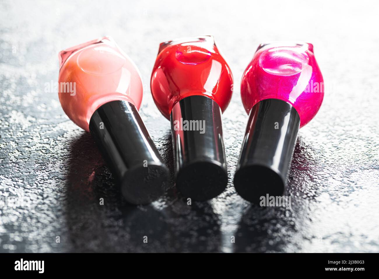 Colorful nail polish bottles on a black table. Stock Photo