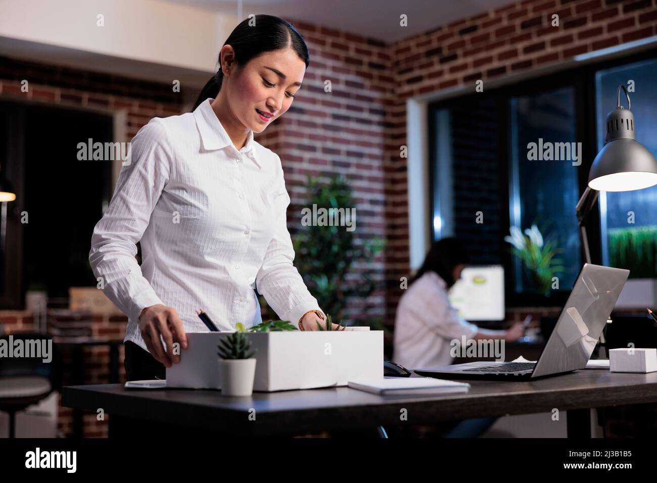 Dismissed business company employee putting personal stuff in cardboard box because of project failure. Fired businesswoman packing personal belongings because of workplace financial problems. Stock Photo