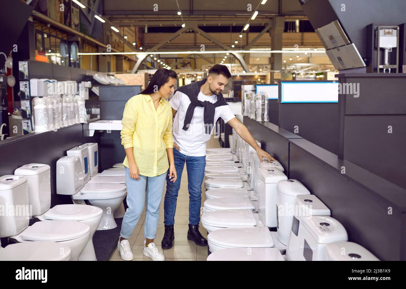 Young couple looking at flush toilets on sale at a modern hardware store or shopping mall Stock Photo