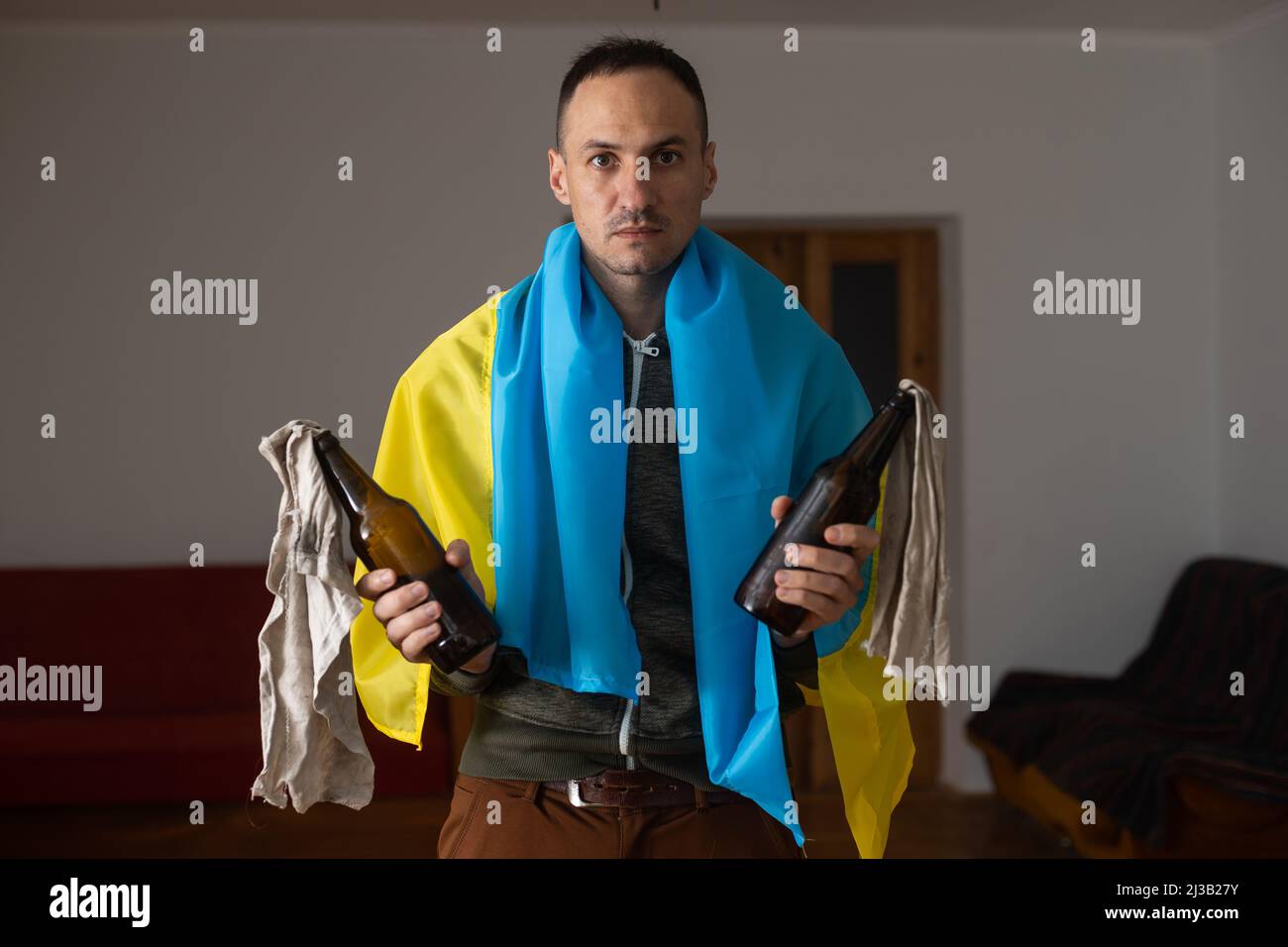 man with flag of ukraine with molotov cocktail in room Stock Photo