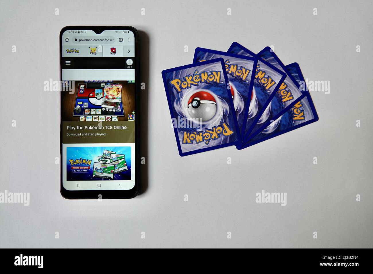 Prague, Czech Republic - April 3 2022: Back side of Pokemon cards and smartphone smart phone with open online version of Pokemon Trading Card Game. Stock Photo