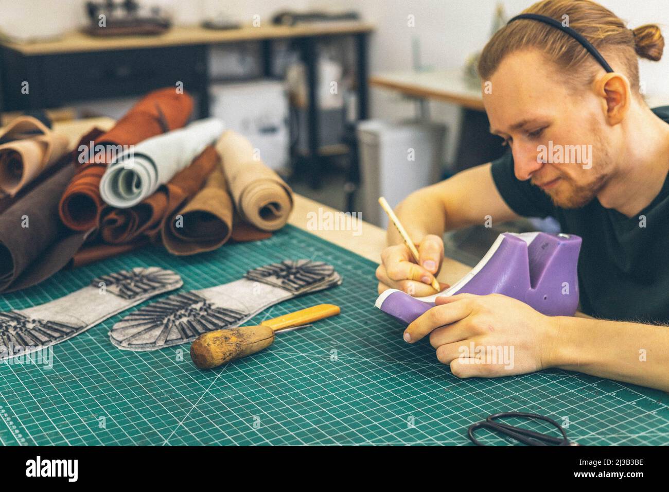 Craftsman drawing shoe last pattern creating leatherwork at studio ...