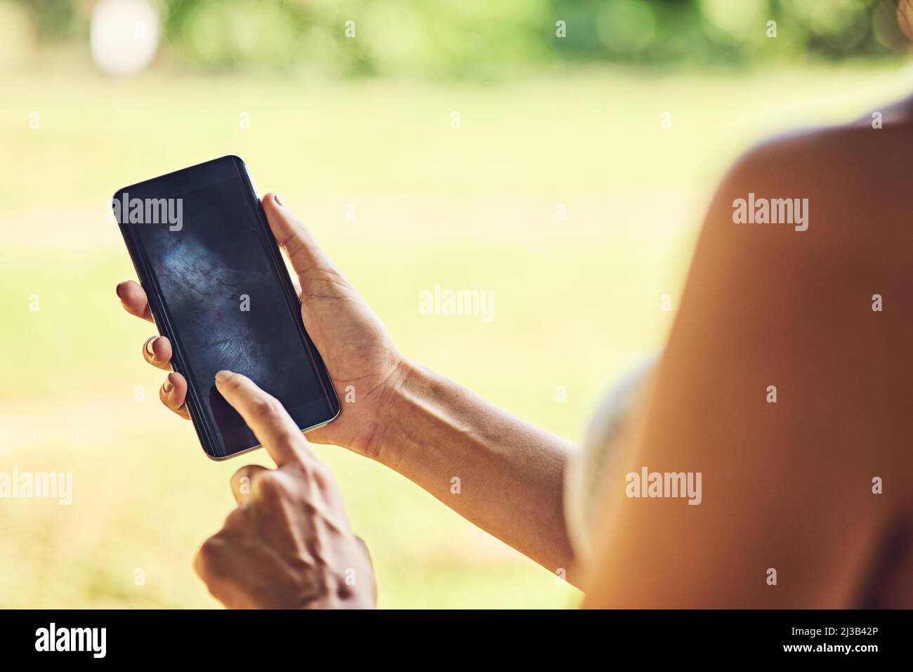 Got your device updated with the latest apps. Closeup shot of an unrecognizable woman using a cellphone outdoors. Stock Photo