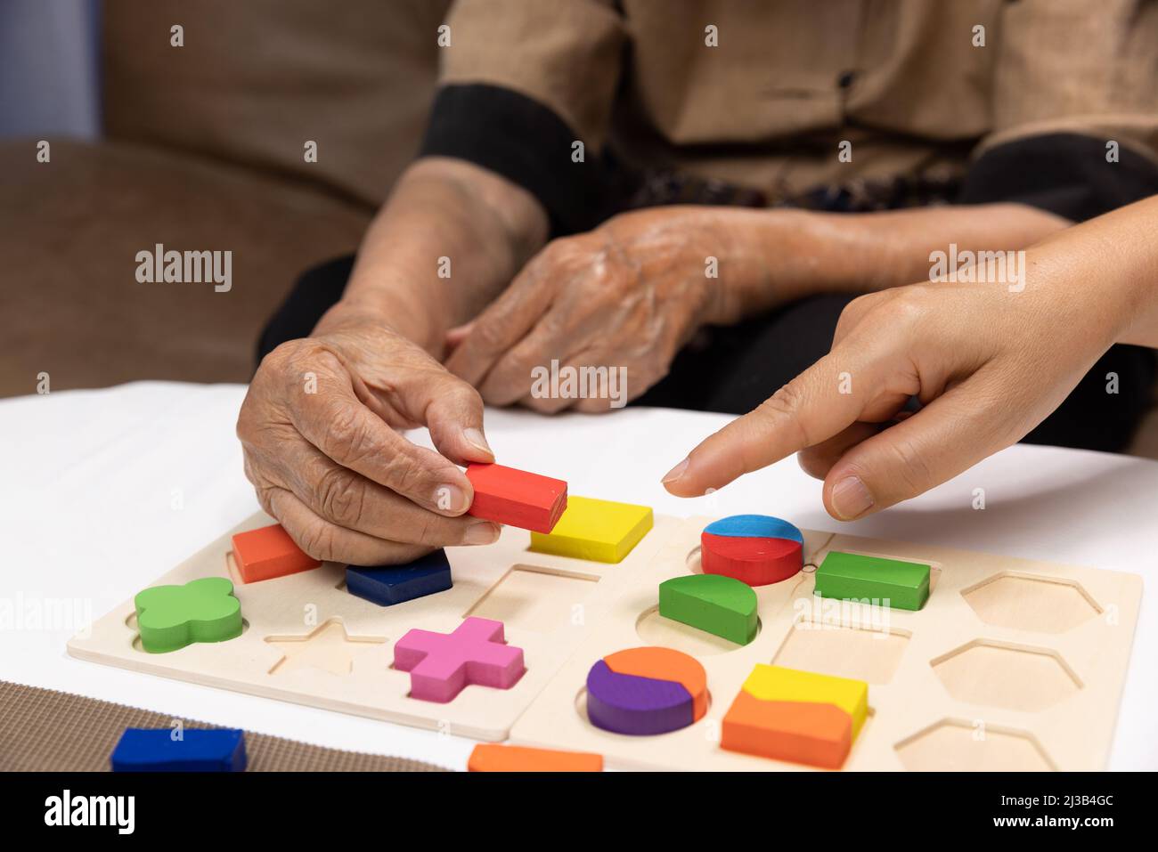 Caregiver and senior woman playing wooden shape puzzles game for