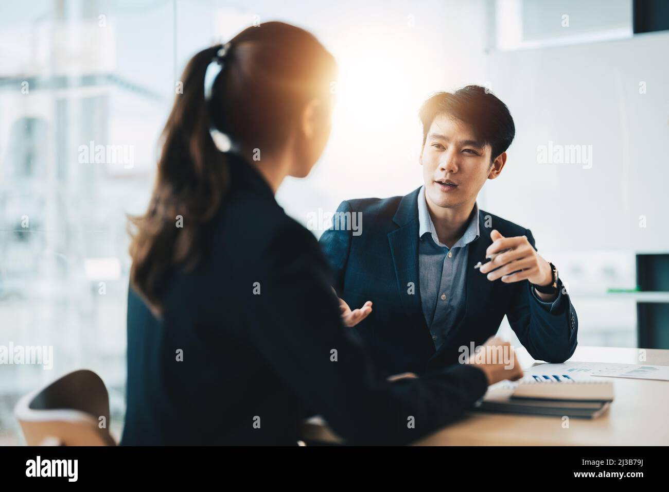 Two diverse asian business people discussing work together in an office Stock Photo