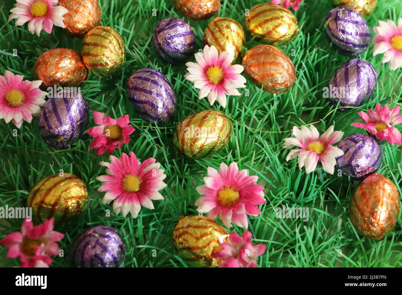 colorful easter eggs with pink flowers on grass background Stock Photo