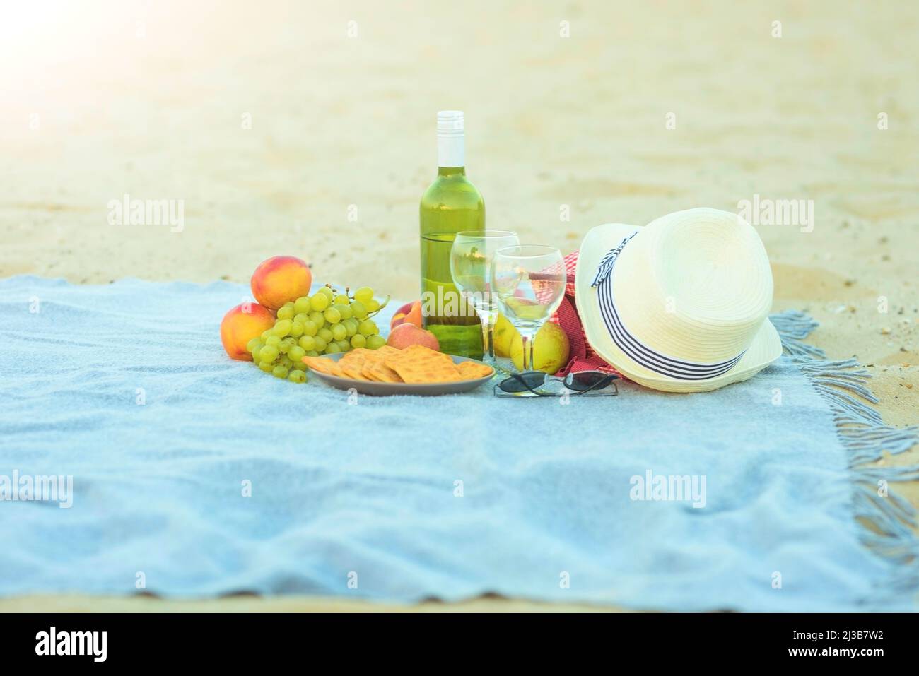 Picnic background with bag, grape and white wine on the beach by blue ...