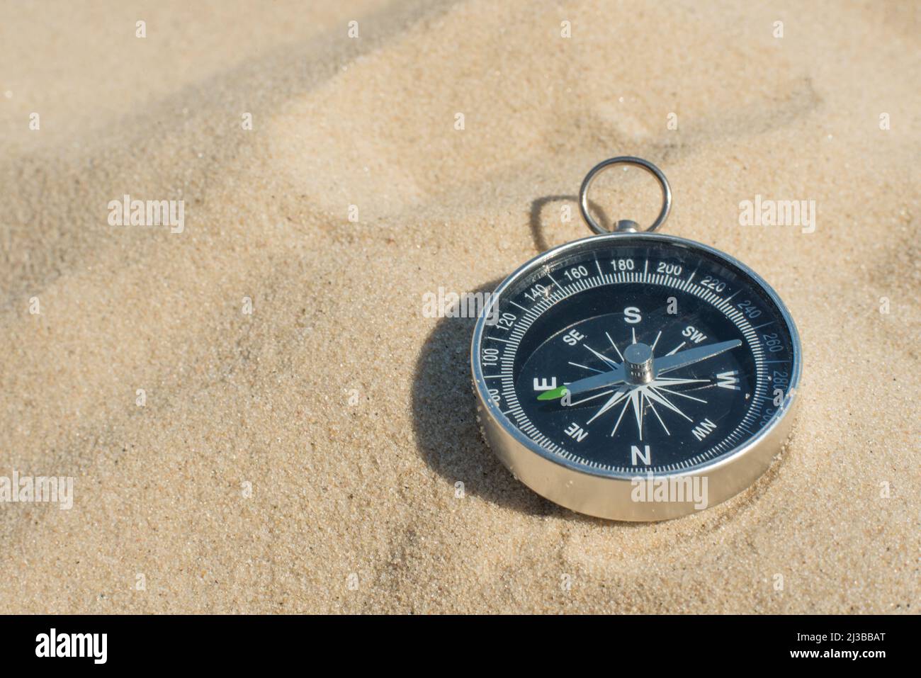 Compass buried in the sand on the beach concept of lost or direction ...