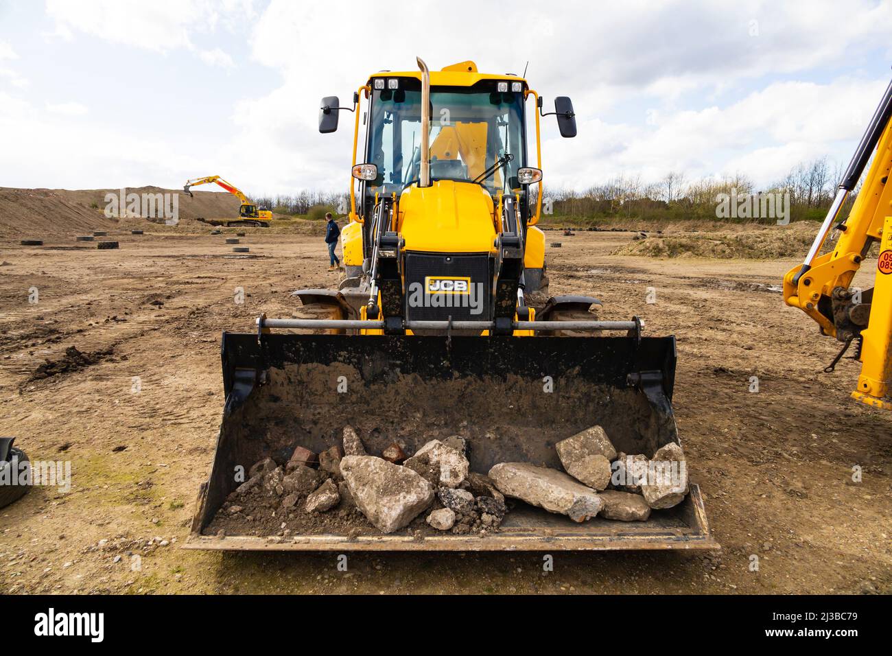 JCB 3CX backhoe loader digger with bucket full of rubble. Diggerland, Castleford, Yorkshire, England Stock Photo