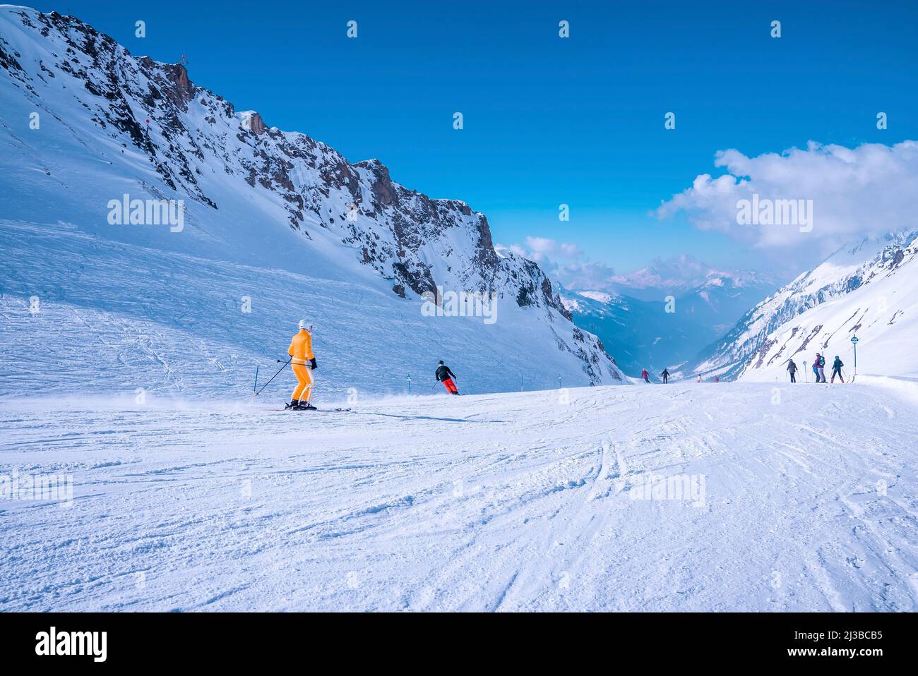 Skiers sliding down snowy slope on mountain at winter resort Stock