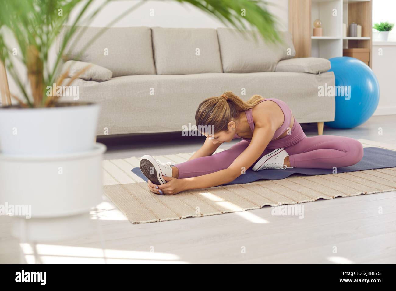 Athletic young woman in morning at home doing stretching before doing physical exercises. Stock Photo