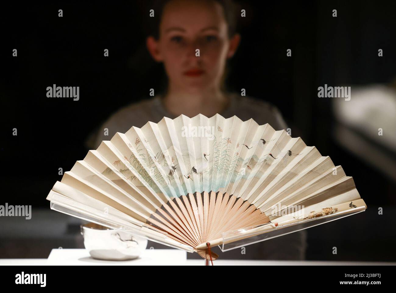 A gallery employee poses with Japanese folding fan, that was gifted to