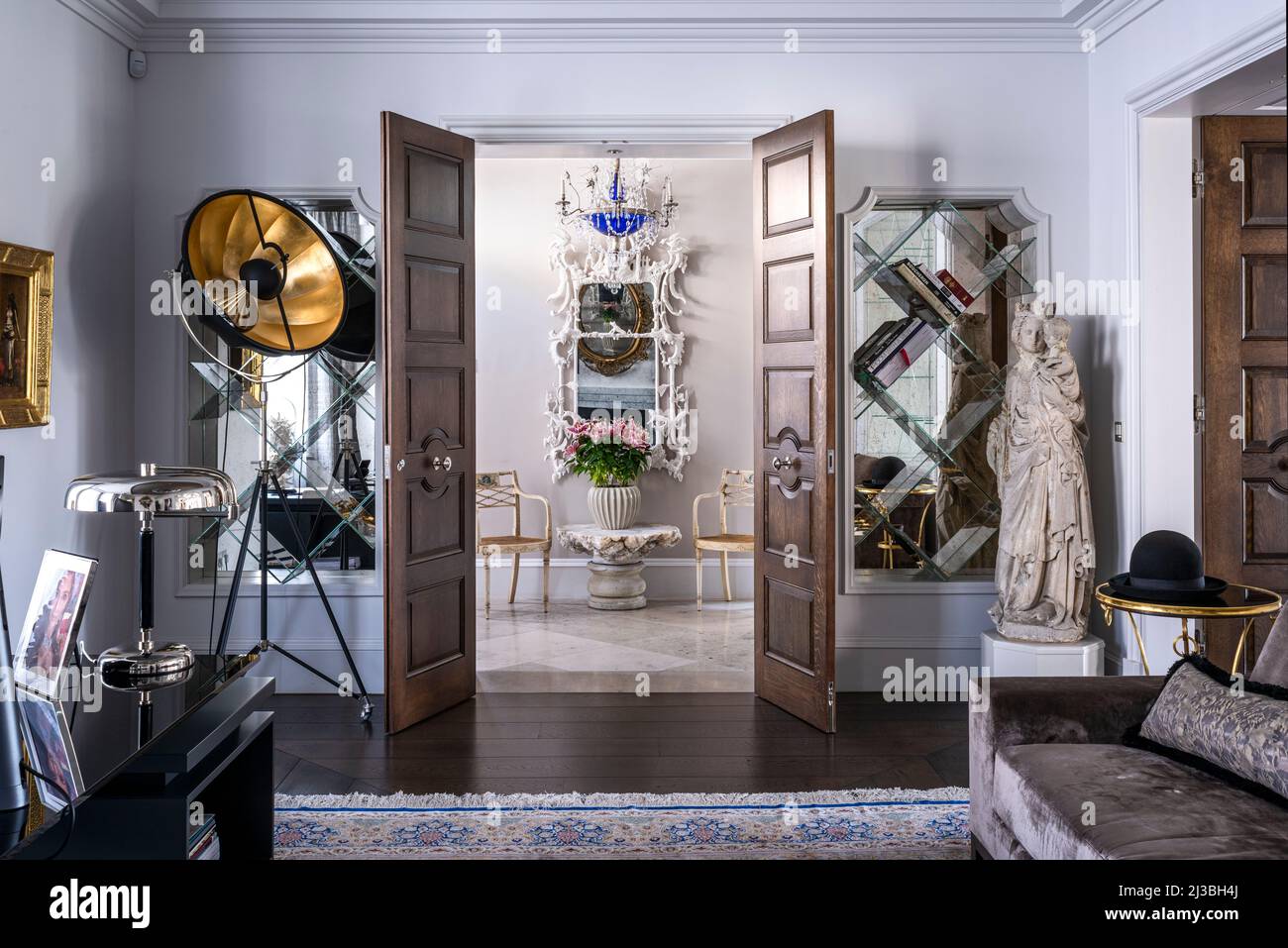 Vintage tripod lamp and statue with view of chinoiserie mirror and Regency armchairs in Holland Park home, London, UK Stock Photo