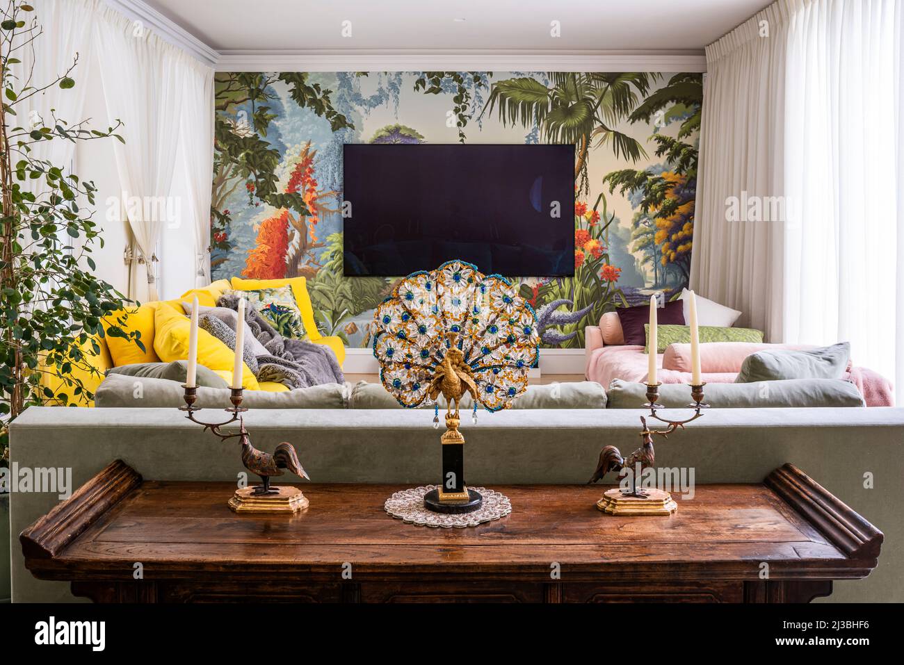 1930s peacock table lamp on antique Chinese elmwood cabinet with sofa by Christian Liaigre; and de Gournay's Eden wallpaper, Holland Park, London, UK Stock Photo