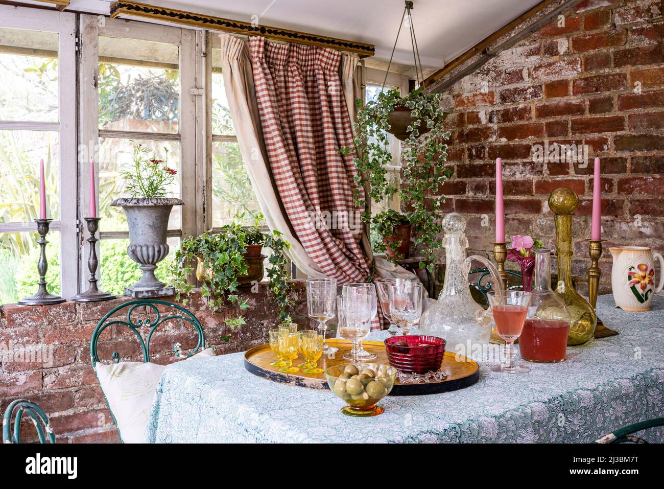 Gingham curtains and exposed brickwork in farmhouse conservatory, 17th century Suffolk home, UK Stock Photo