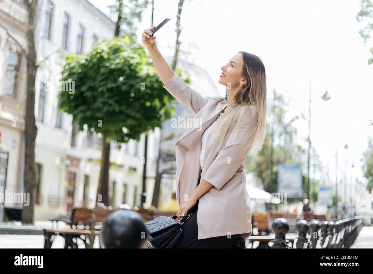 young woman taking a selfie while walking in the city. Stock Photo