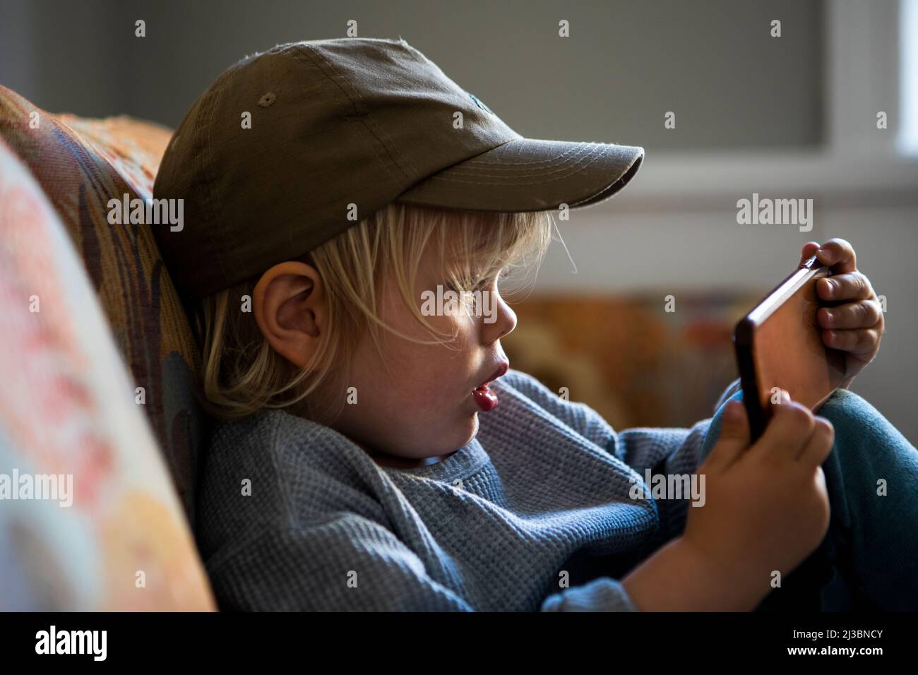 Boy in baseball cap using smart phone Stock Photo