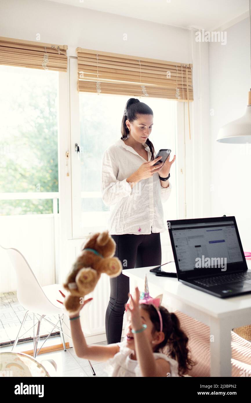 Woman in kitchen using cell phone Stock Photo