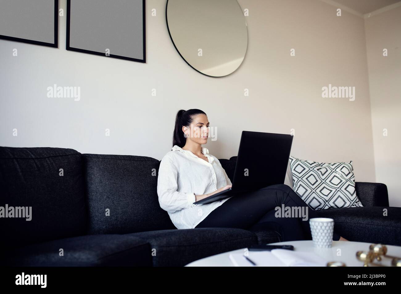 Woman on sofa using laptop Stock Photo