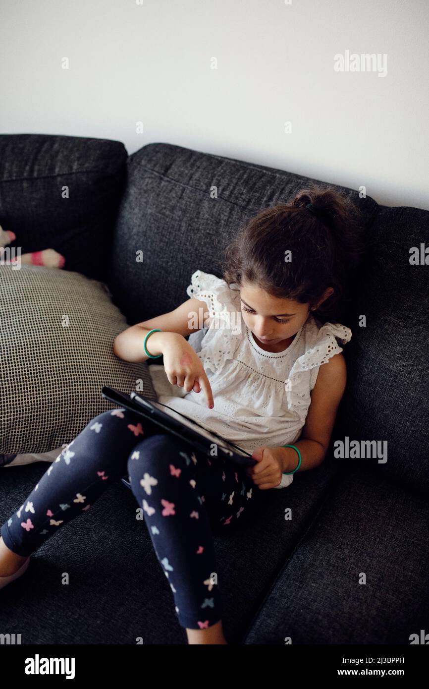Girl using digital tablet on sofa Stock Photo