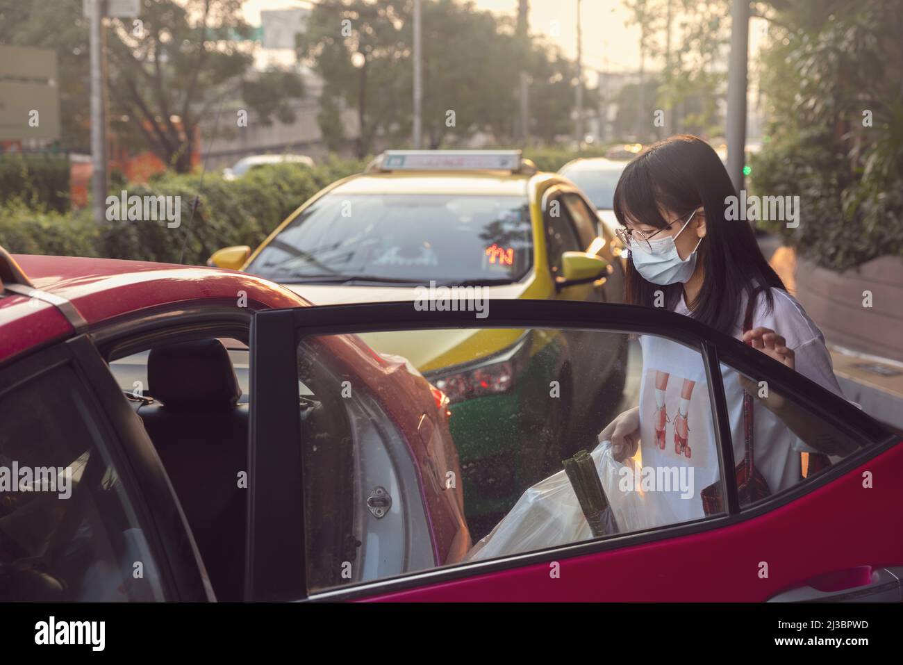 Woman in protective face mask getting into taxi Stock Photo Alamy