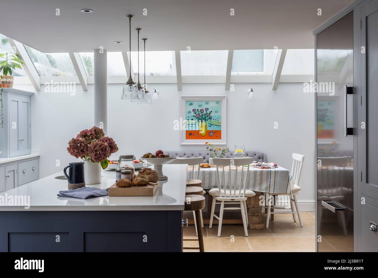 Table and chairs under skylight with glass pendant lights in kitchen of renovated St Ives home, Cornwall, UK Stock Photo