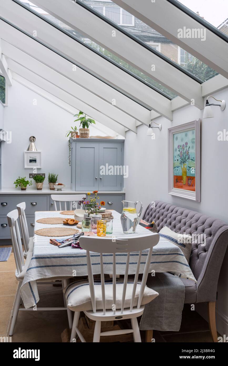 Table and chairs with bench under skylight in renovated St Ives home, Cornwall, UK Stock Photo