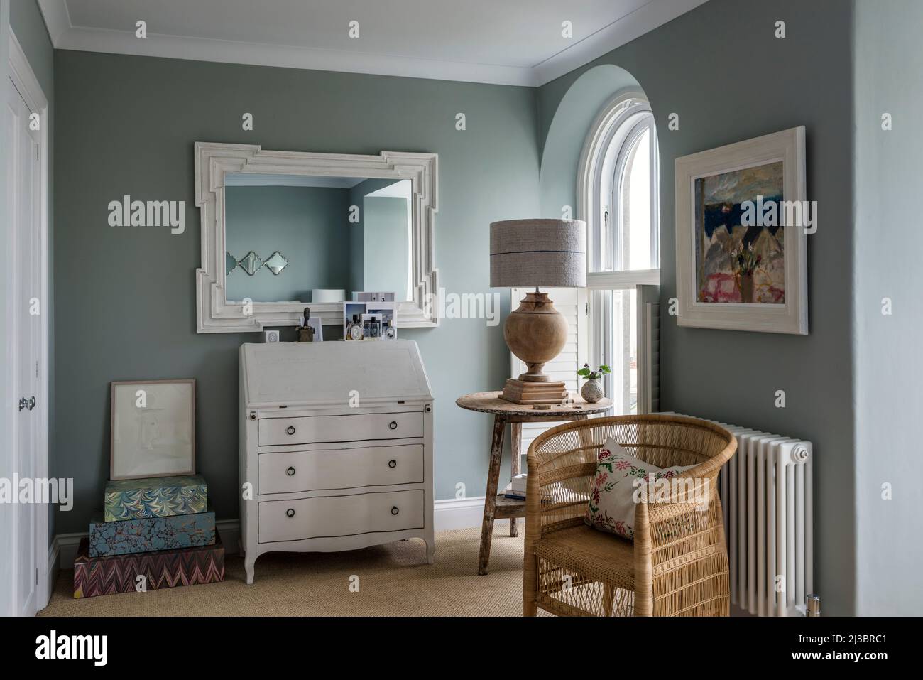 Mirror above bureau with wicker chair at arched window in renovated St Ives home, Cornwall, UK Stock Photo