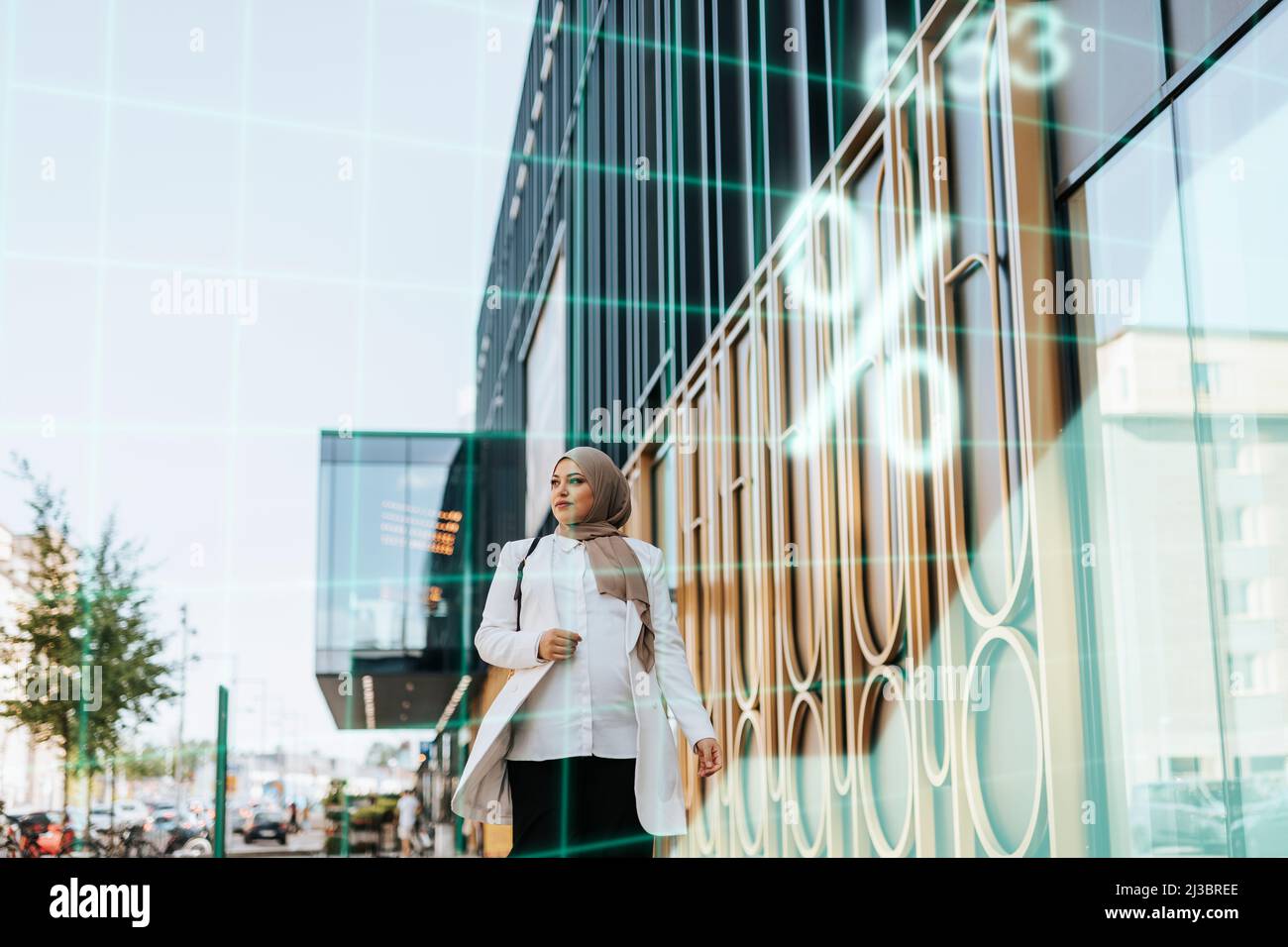 Young businesswoman walking along office building Stock Photo