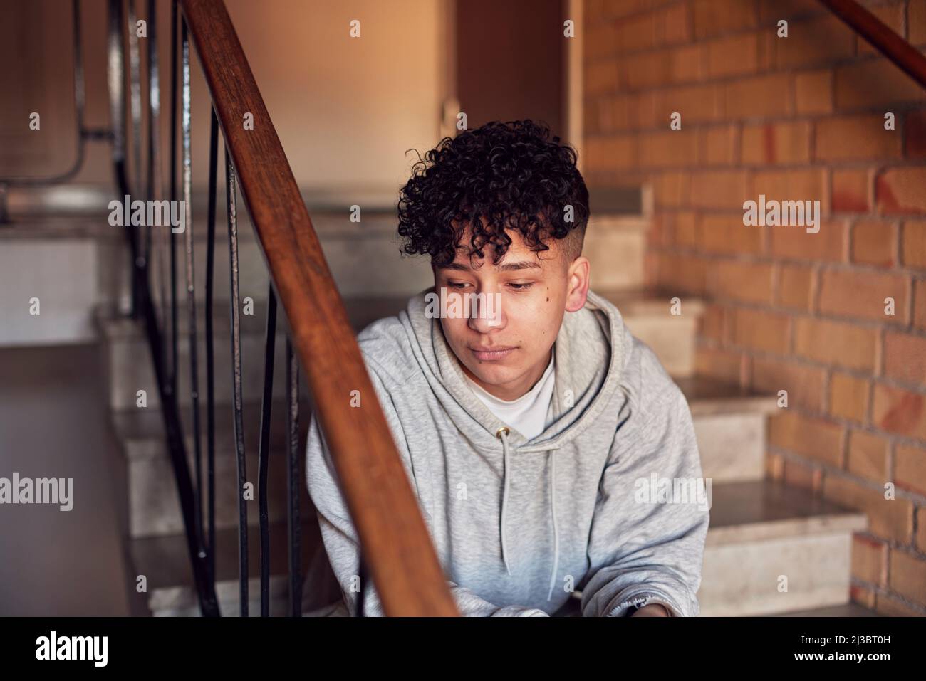 Boy sitting on stairs in residential building Stock Photo