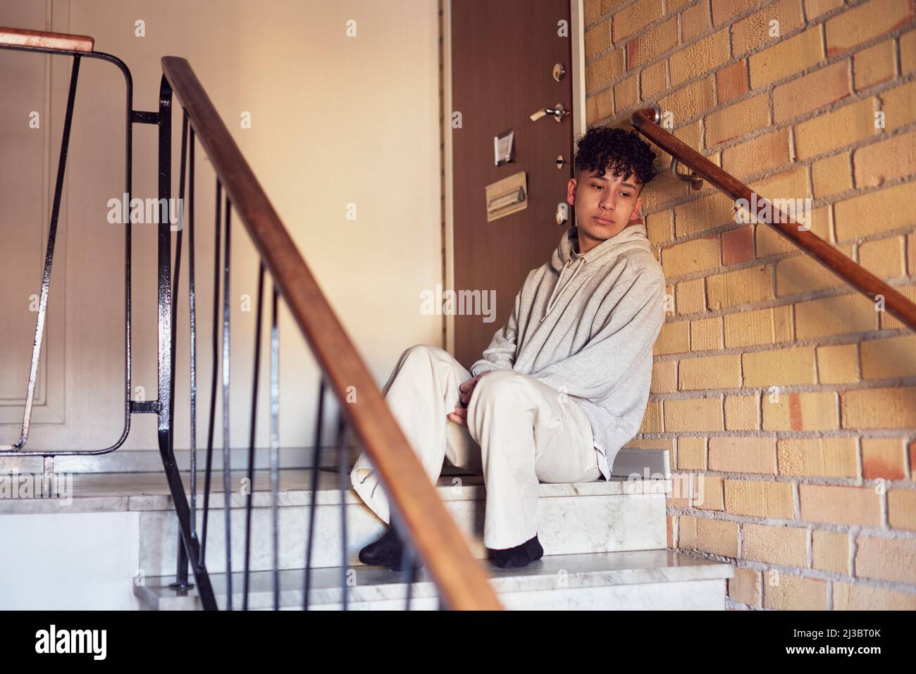 Boy sitting on stairs and leaning against wall Stock Photo