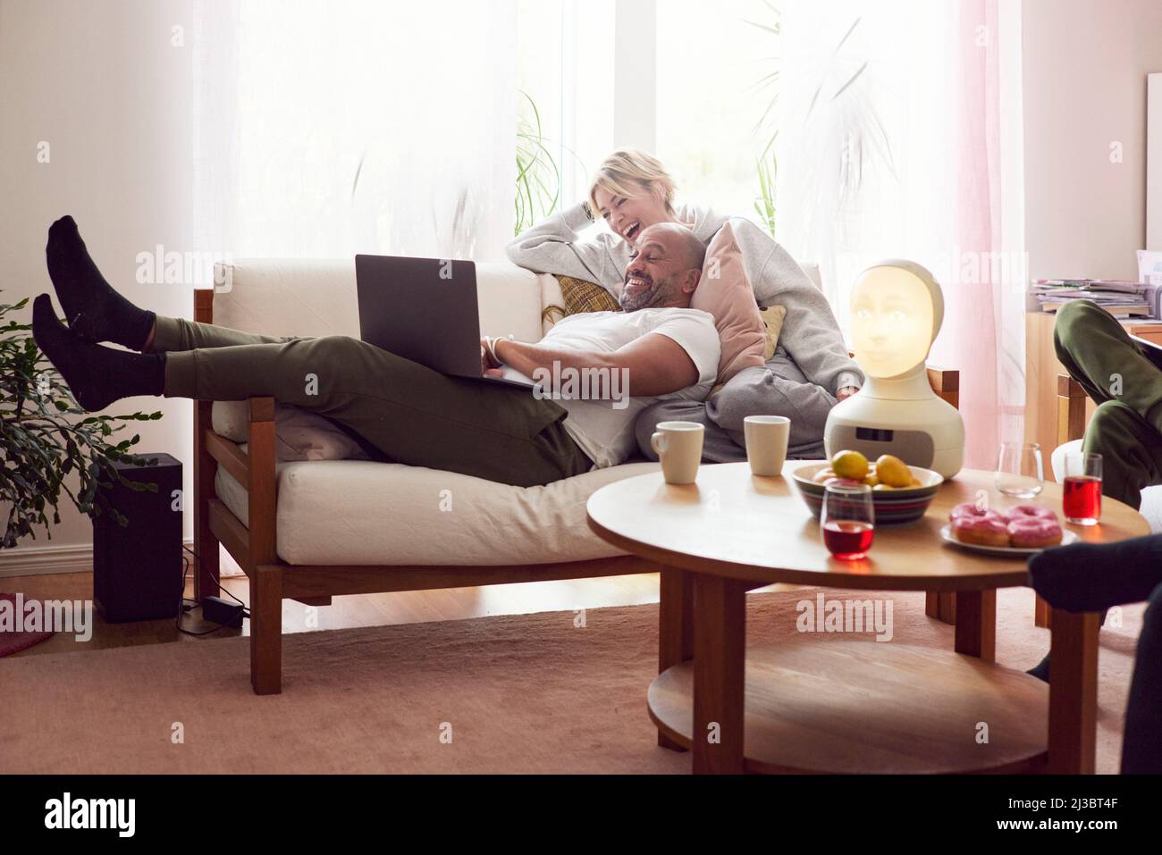 Smiling couple using laptop on sofa Stock Photo