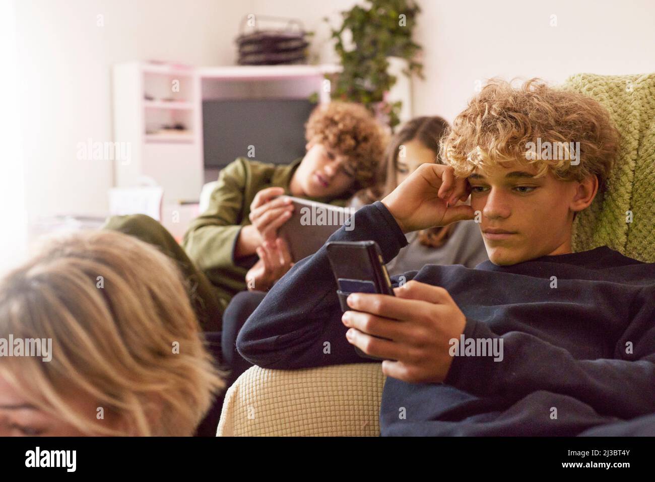 Siblings using electronic devices at home Stock Photo
