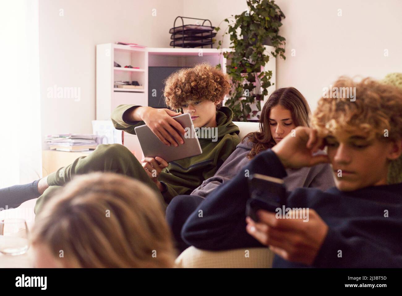 Siblings using electronic devices at home Stock Photo