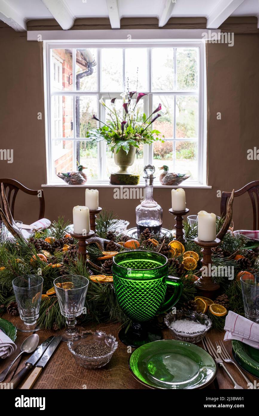 Wooden candlesticks with orange and pine centrepiece on dining table at