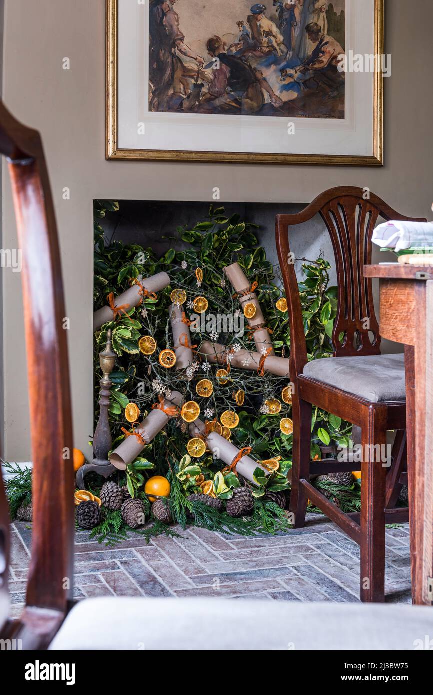 Christmas crackers and sliced orange display in fireplace of 18th century Suffolk cottage at Christmas, UK Stock Photo