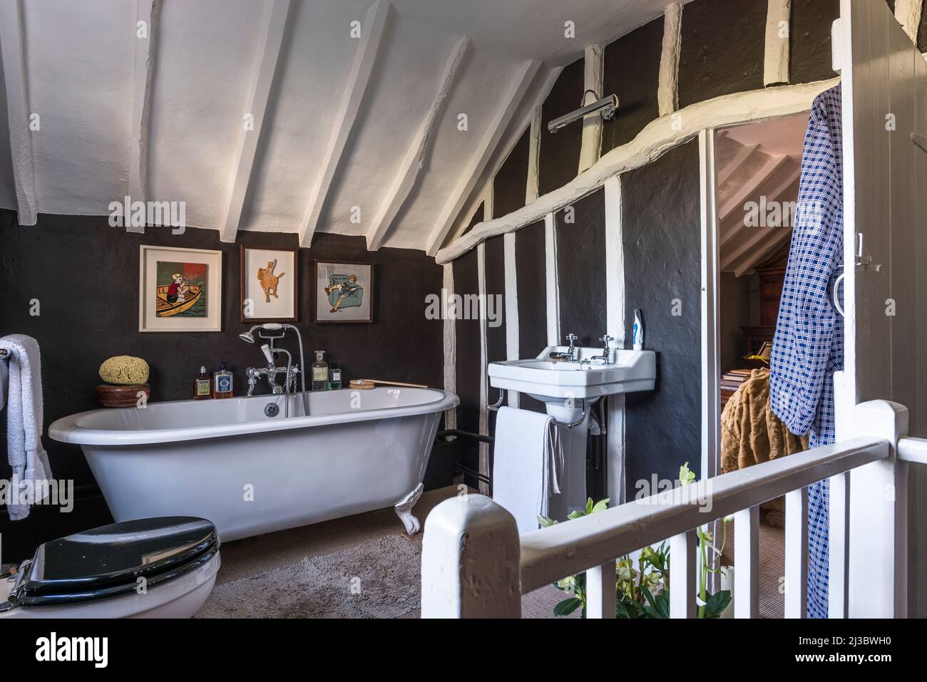 Freestanding bath and black walls in attic bathroom of 18th century Suffolk cottage, UK Stock Photo