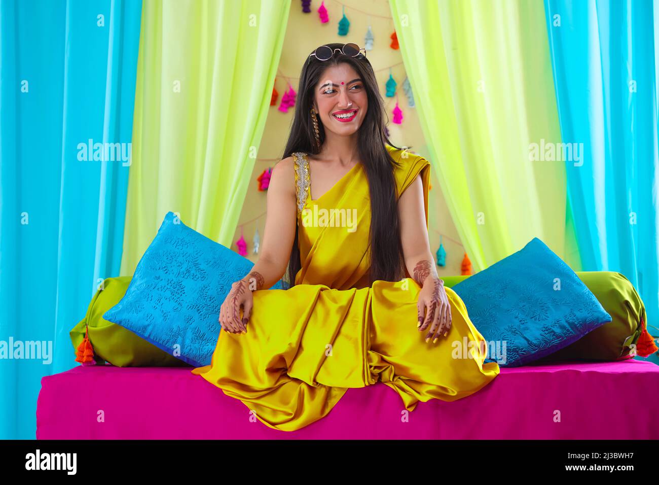 Indian happy bride sitting on stage and smiling during haldi ceremony Stock Photo