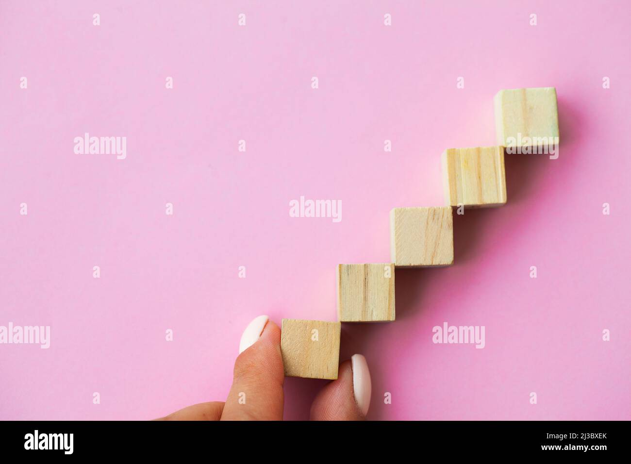 Hand arranging wood cube stacking as step stair Stock Photo - Alamy