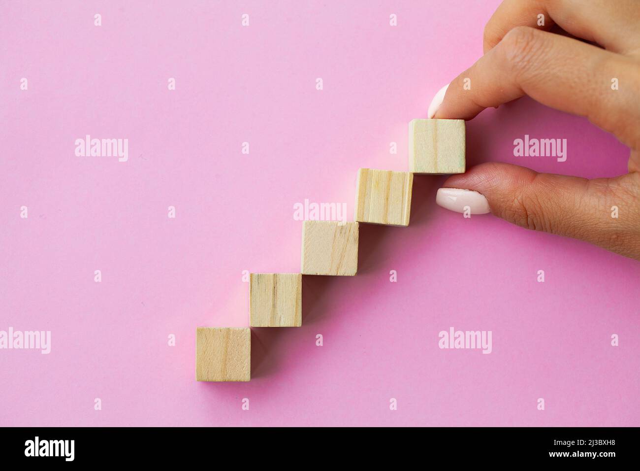 Hand arranging wood cube stacking as step stair Stock Photo - Alamy