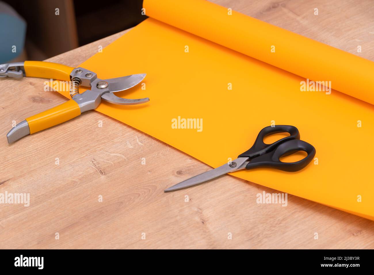 Close-up of a roll of orange wrapping paper, scissors, pruning