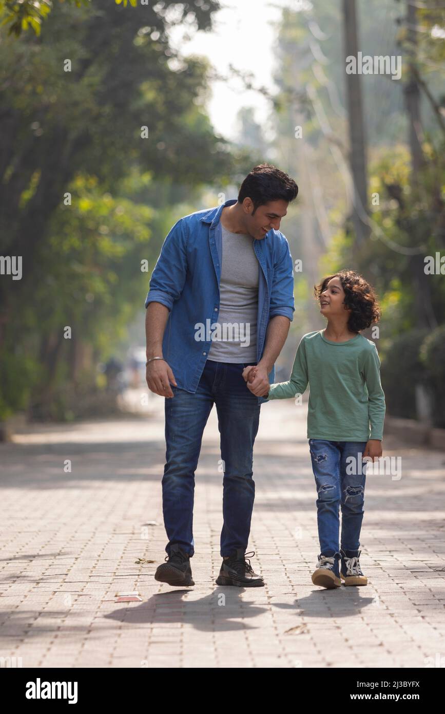 Father with his son holding hands and walking in the park Stock Photo ...