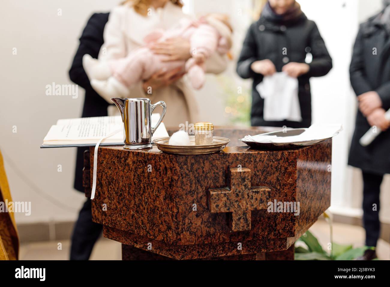 Child catholic baptisms. A mother holds her baby over a font in a Catholic church. Stock Photo