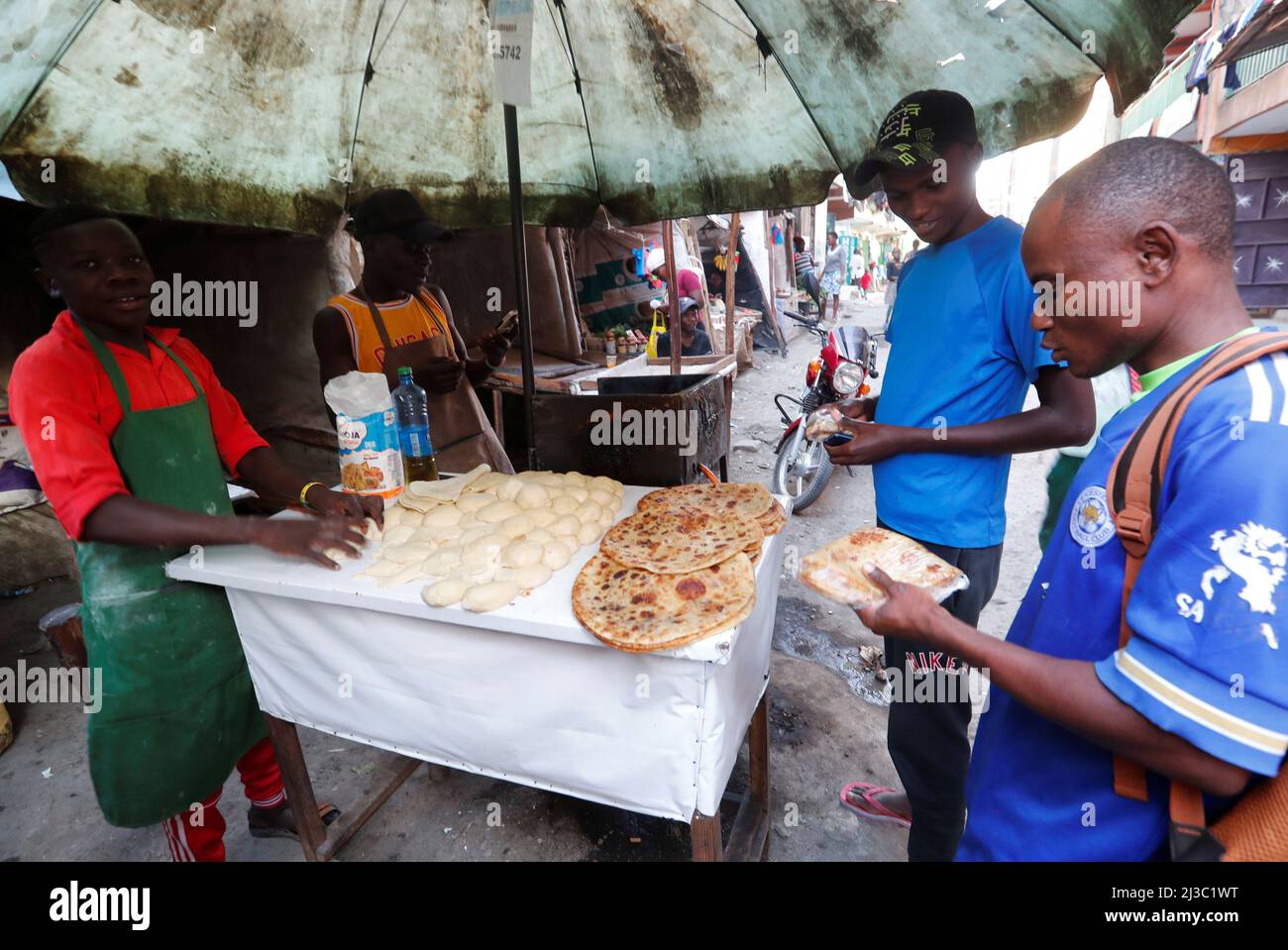 Customers buy chapati bread made from wheat flour at an open kiosk at