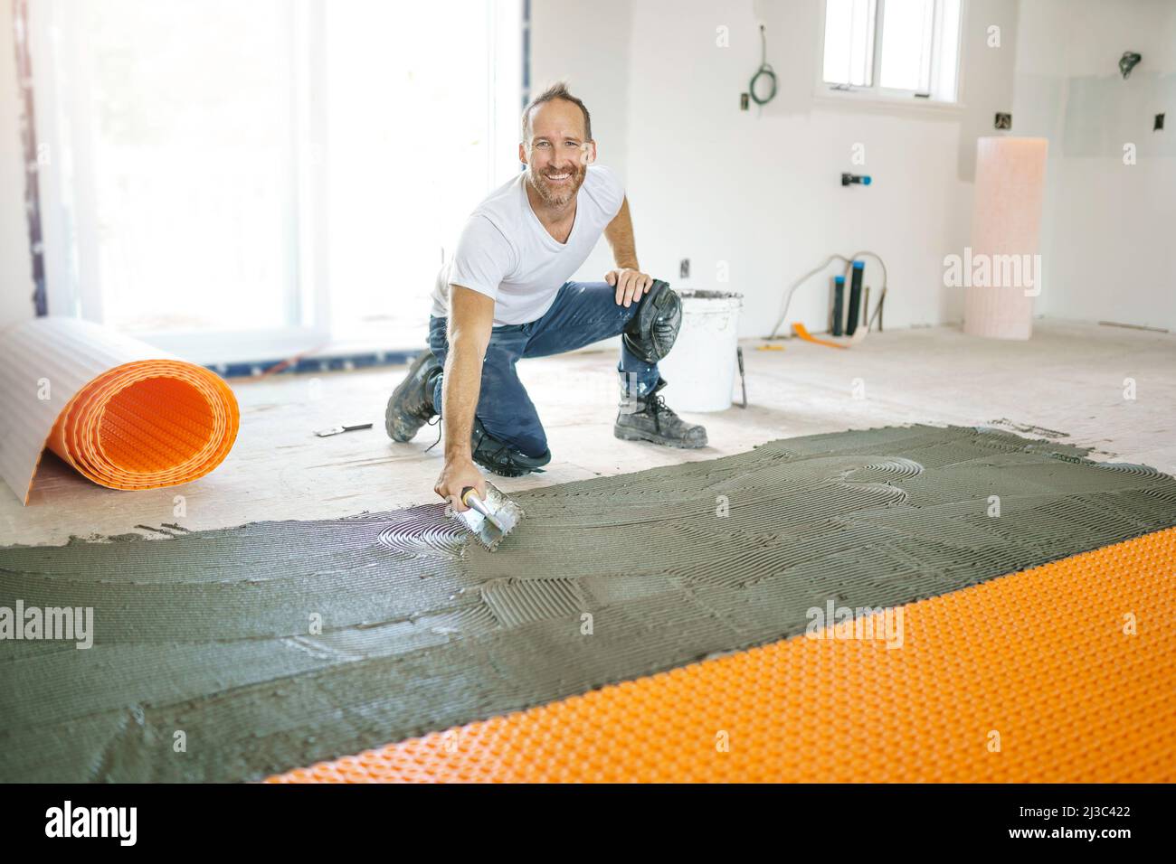 Man worker install orange roll membrane waterproofing on the floor