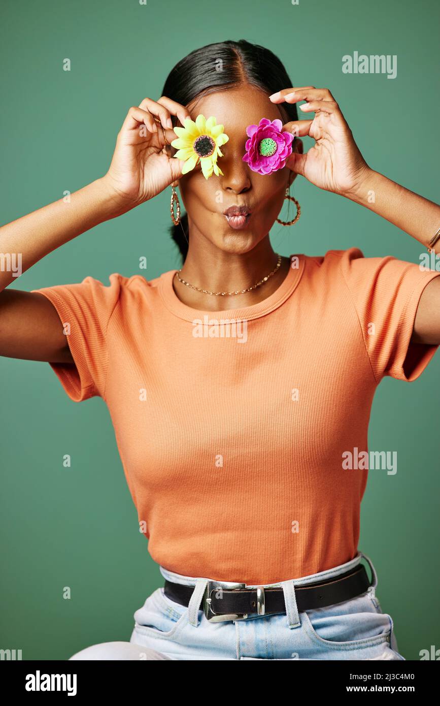 Flower power to the people. Shot of a young woman covering her eyes with two flowers shot against a studio background. Stock Photo