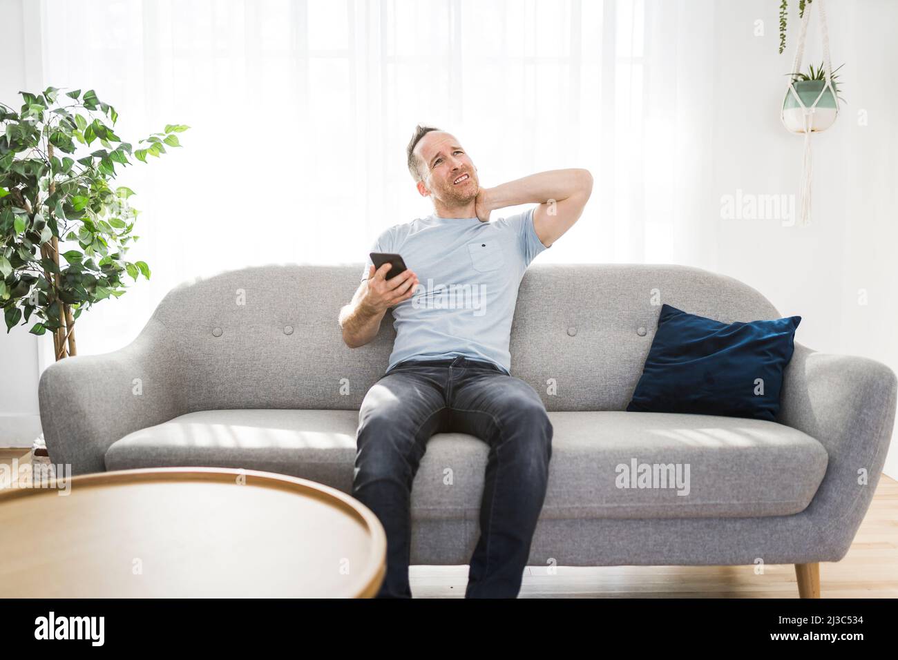 man sitting on couch touching massaging neck he suffering from neck