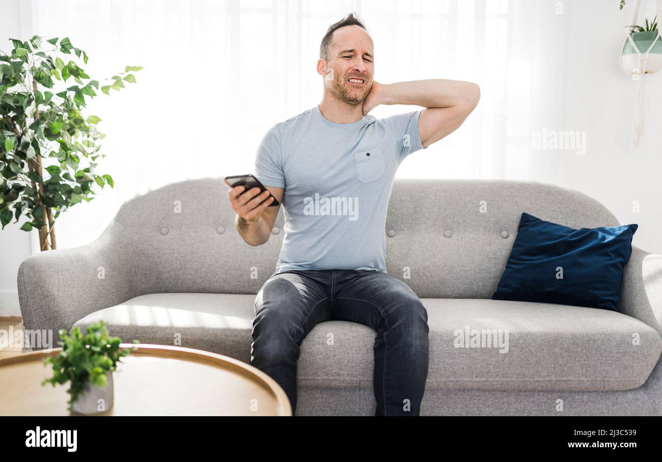 man sitting on couch touching massaging neck he suffering from neck