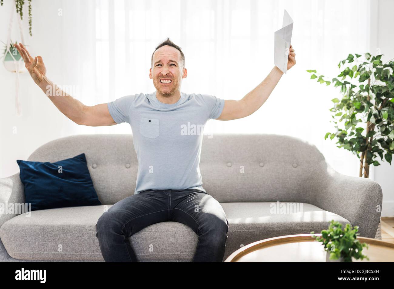Shocked man holding some documents on sofa livingroom Stock Photo